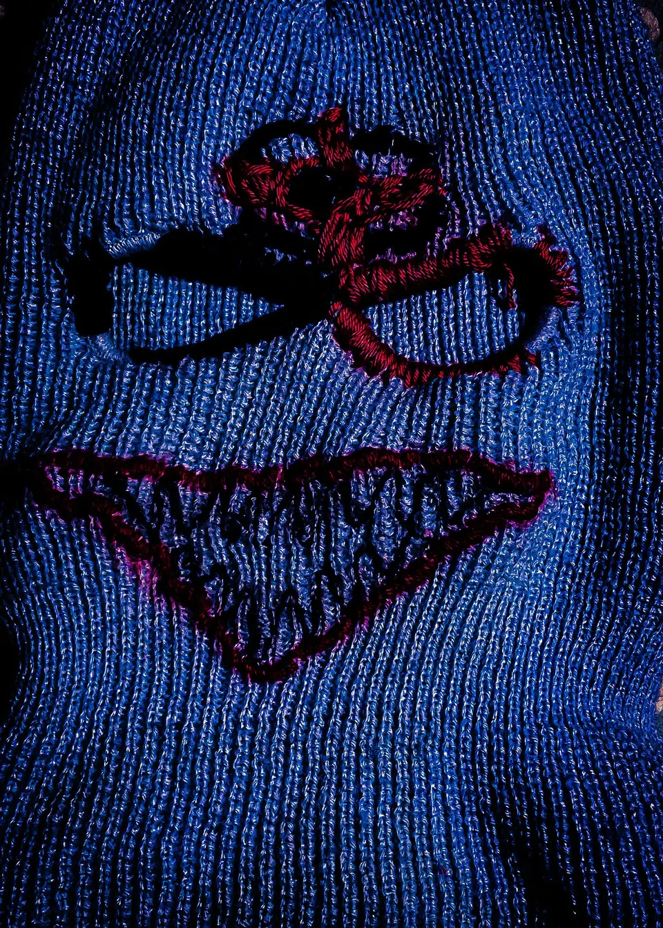 Cagoule nº 1 à plat, filtre bleu : broderie épaisse autour des yeux et bouche en triangle remplie de dents en zigzag