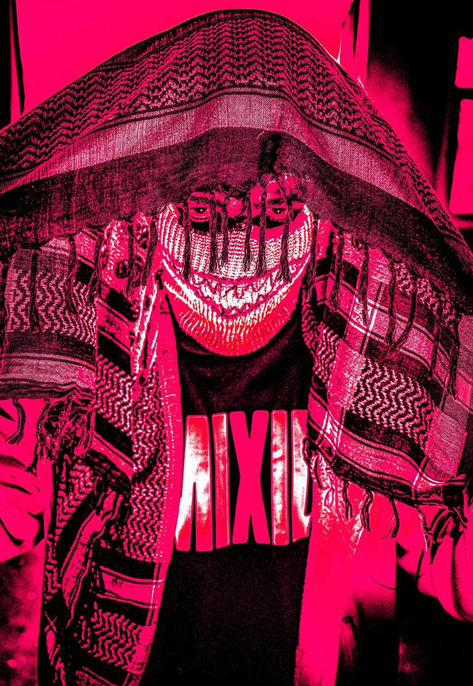 Personne portant une cagoule claire aux dents brodées, sous un keffieh, lumière rose